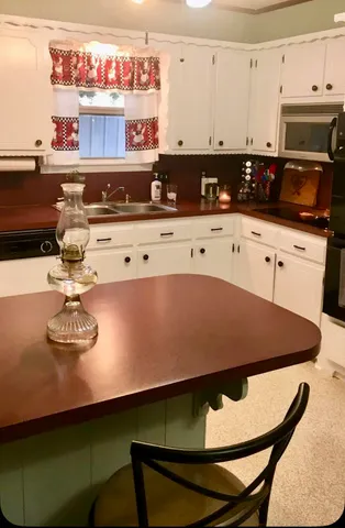 a kitchen with stainless steel appliances a refrigerator a sink a stove a microwave and white cabinets