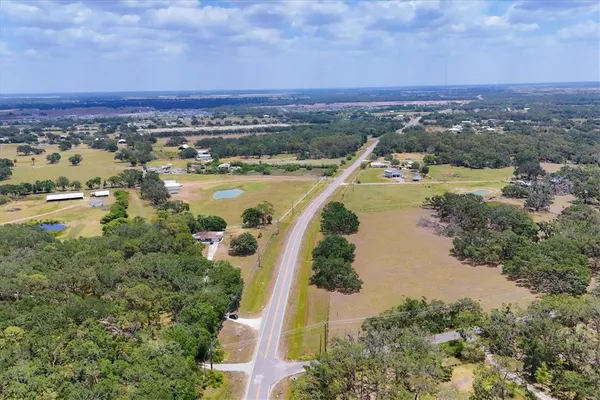 a view of a road with a big yard and a large tree in the background