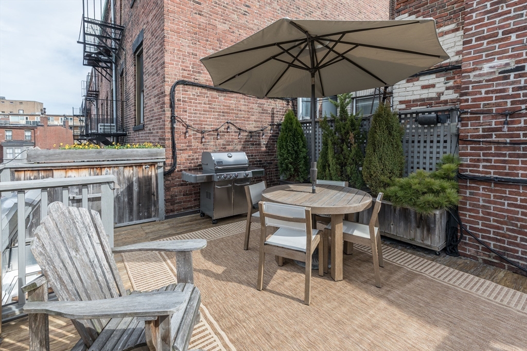 3 River St Place Boston, MA 02114 - Photo 26 of 28 a patio with a table and chairs under an umbrella