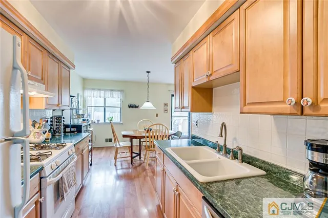 a kitchen with stainless steel appliances granite countertop a sink a stove and a wooden floors
