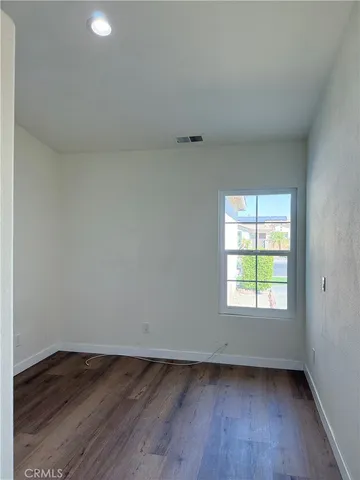 an empty room with wooden floor and window