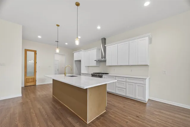 a kitchen with a sink a stove cabinets and wooden floor