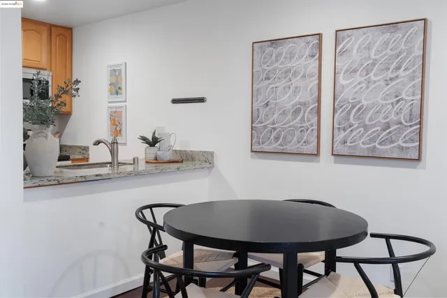 a kitchen with stainless steel appliances kitchen island granite countertop a refrigerator a stove a oven a sink a dining table and chairs with wooden floor