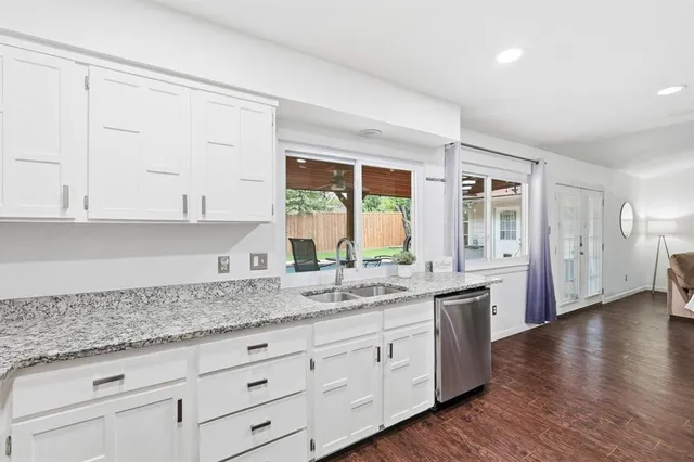 a kitchen with granite countertop white cabinets and a wooden floor