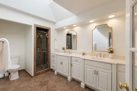 a spacious bathroom with a double vanity sink toilet and a mirror
