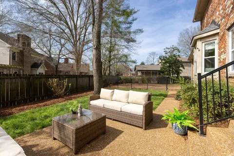 a view of a patio with couches table and chairs with wooden fence and plants