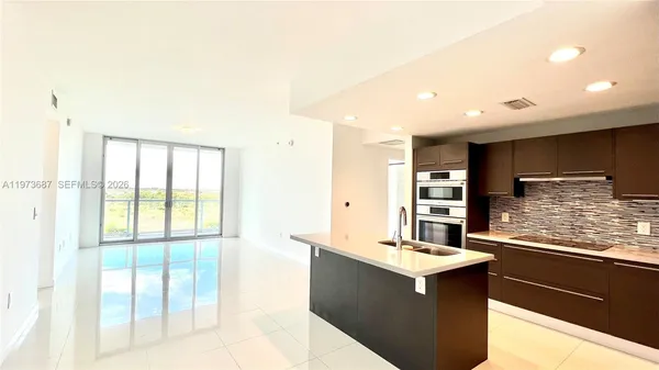 a kitchen with kitchen island and large windows