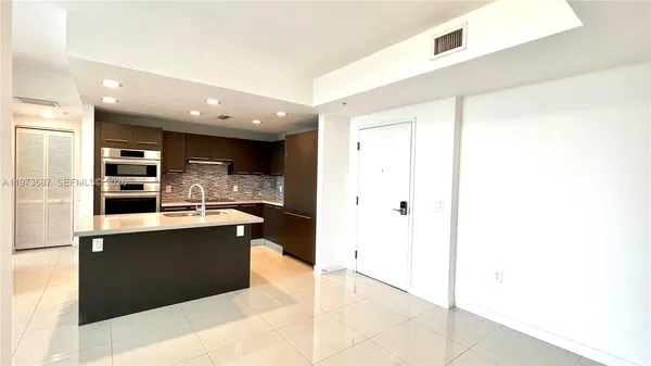a kitchen with stainless steel appliances kitchen island granite countertop a refrigerator and a sink