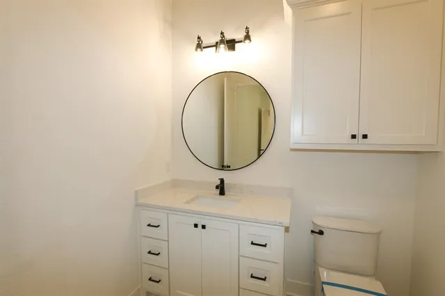 a bathroom with a granite countertop toilet and a sink