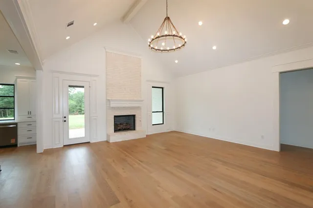 an empty room with wooden floor fireplace and windows