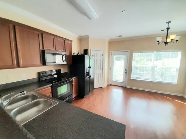 a kitchen with stainless steel appliances granite countertop a refrigerator a stove a sink dishwasher and wooden cabinets with wooden floor