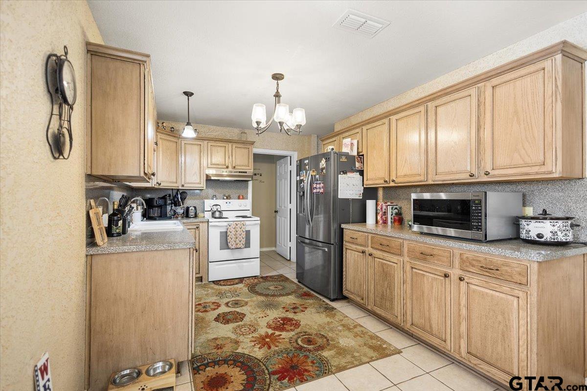 14716 Fox Ridge Tyler, TX 75709 - Photo 11 of 25 a kitchen with granite countertop a refrigerator oven a sink dishwasher and white cabinets with wooden floor
