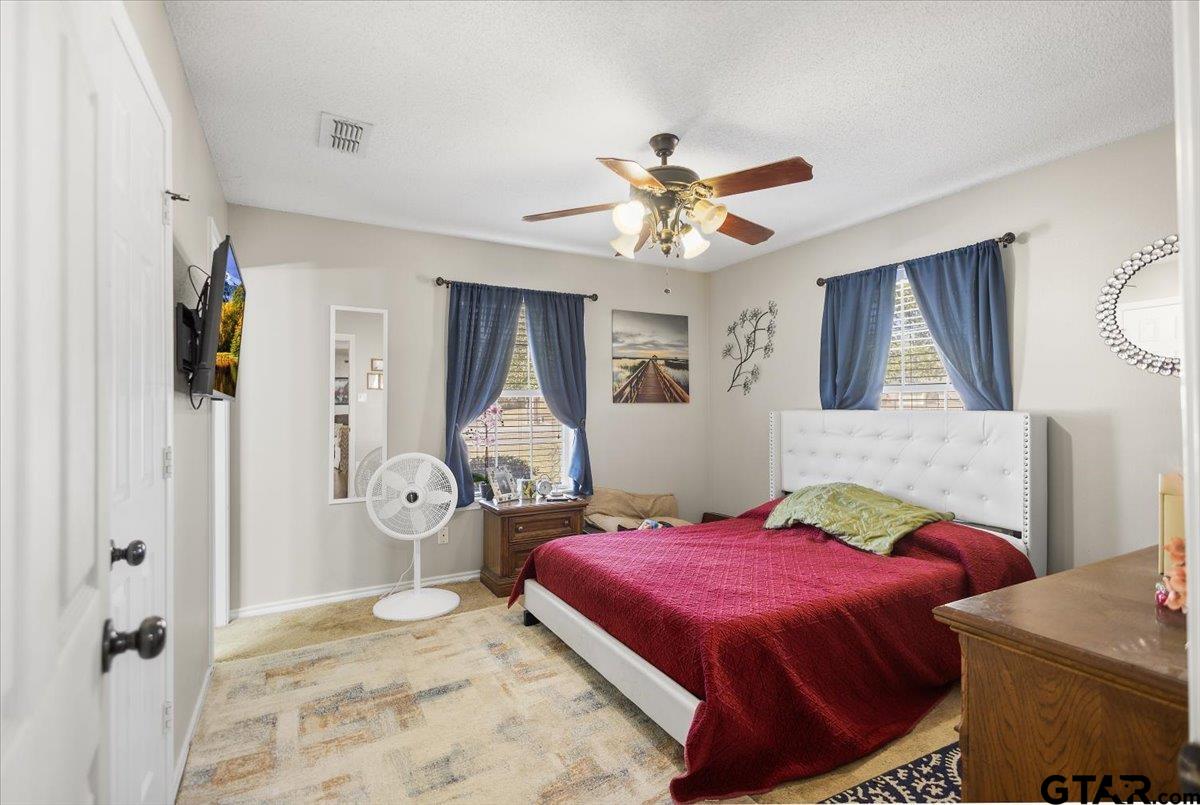 14716 Fox Ridge Tyler, TX 75709 - Photo 12 of 25 a spacious bedroom with a bed and a chandelier