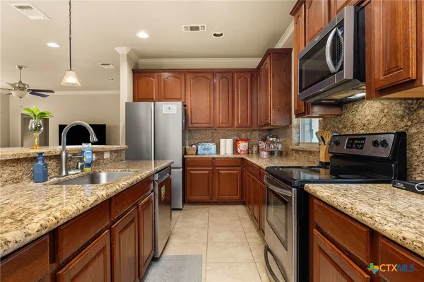 a kitchen with granite countertop stainless steel appliances a sink a counter top space cabinets and a stove