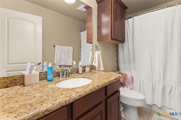 a bathroom with a granite countertop sink toilet and a mirror