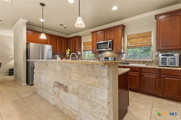 a kitchen with kitchen island granite countertop a sink a counter top space appliances and cabinets