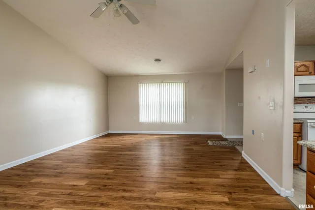 a view of an empty room with window and wooden floor
