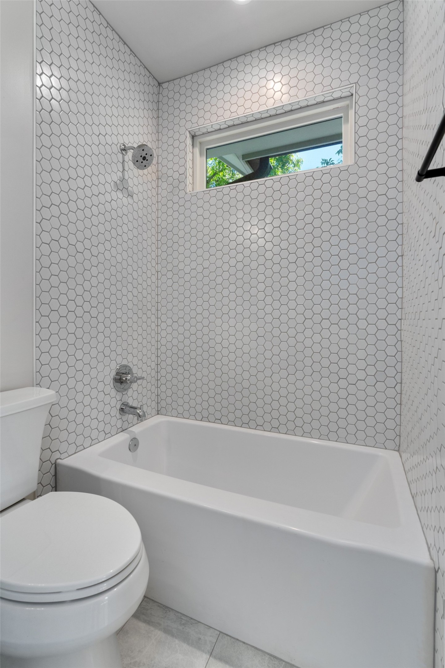 5200 Grover Avenue Austin, TX 78756 - Photo 26 of 32 Full bathroom in secondary bedroom featuring a white ceramic bathtub, chrome shower fixtures, and white hexagonal tile walls