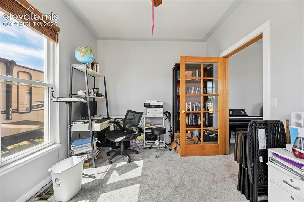 8347 Tibbs Road Peyton, CO 80831 - Photo 21 of 39 Carpeted room with a large window featuring wood-finish blinds, light gray walls, white trim, and a wood-frame door with glass panels