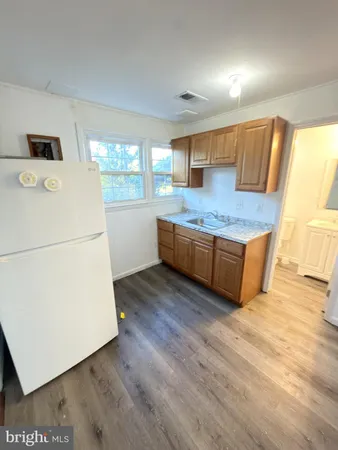 a kitchen with stainless steel appliances granite countertop a stove a refrigerator a microwave oven with white cabinets and wooden floor