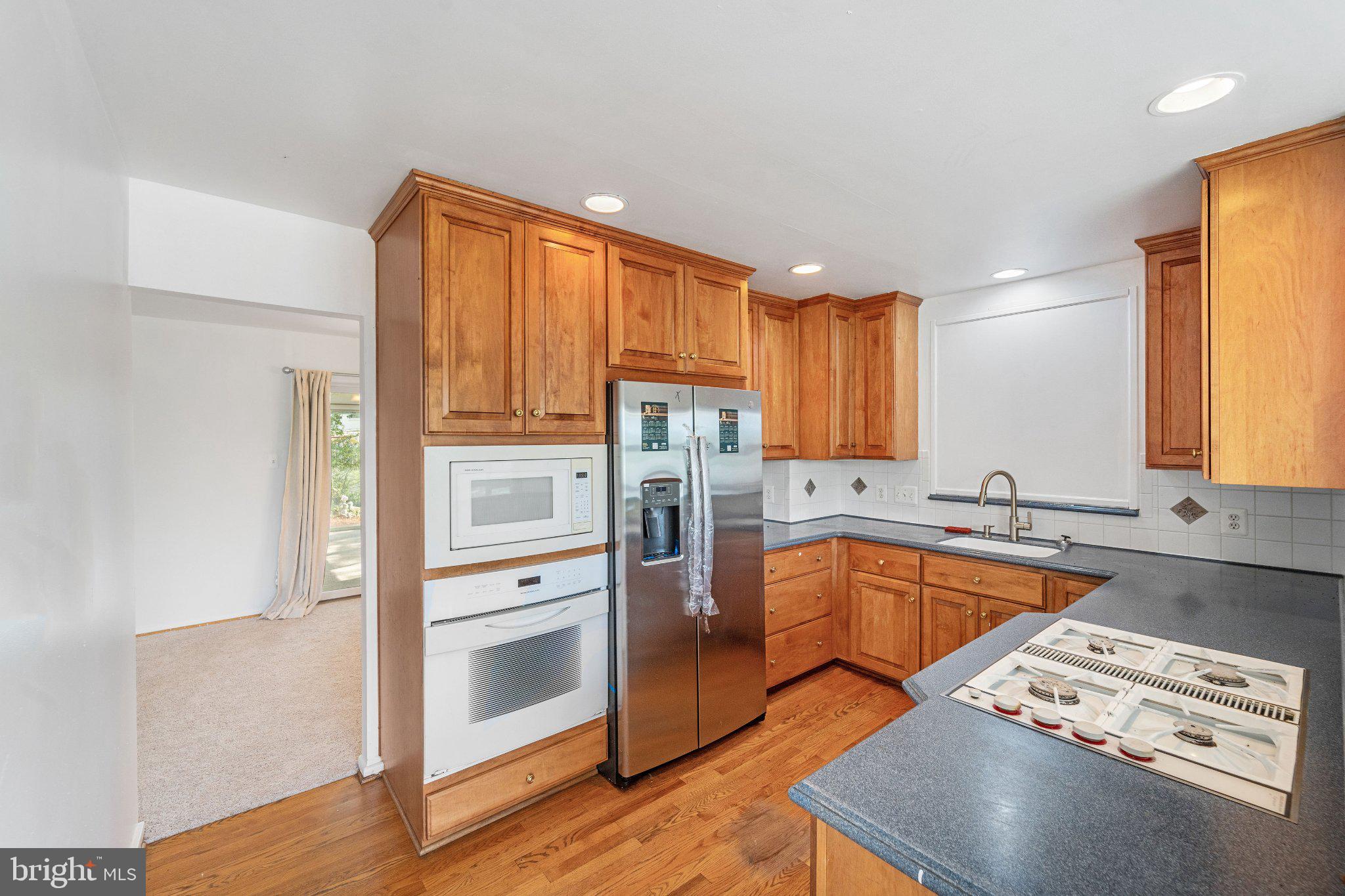 6423 Cabell Court Springfield, VA 22150 - Photo 12 of 58 a kitchen with stainless steel appliances granite countertop a refrigerator a sink dishwasher a stove and white countertops with wooden floor