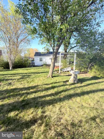 a view of a house with a big yard and large trees
