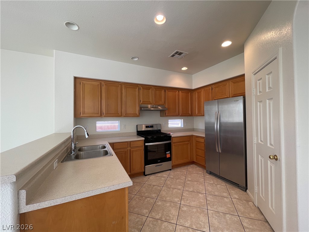 Warm wood cabinetry highlights this functional kitchen layout complete with tile flooring.