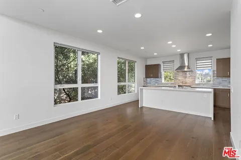 a large kitchen with stainless steel appliances granite countertop a large window and a refrigerator