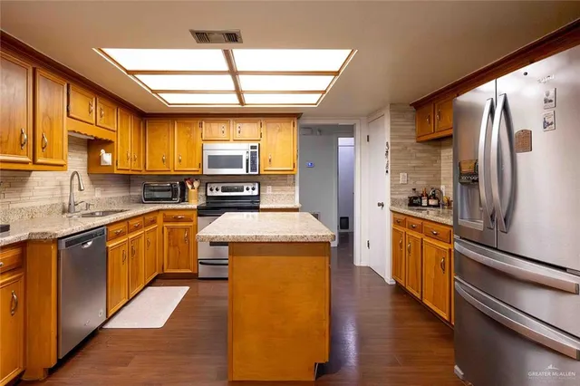 a kitchen with stainless steel appliances granite countertop a sink and a wooden cabinets