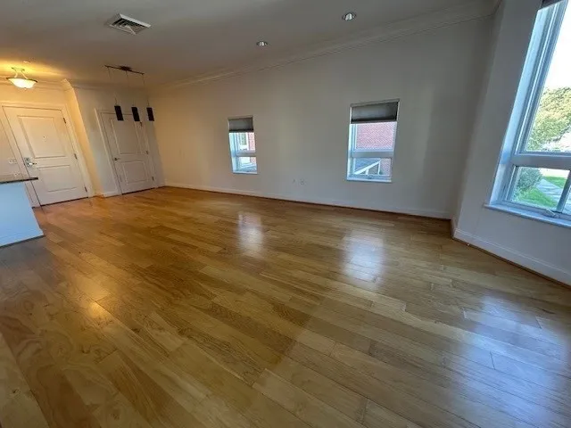 an empty room with wooden floor and windows