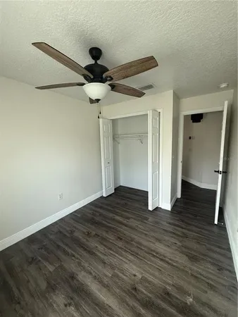 a view of an empty room with window and chandelier fan