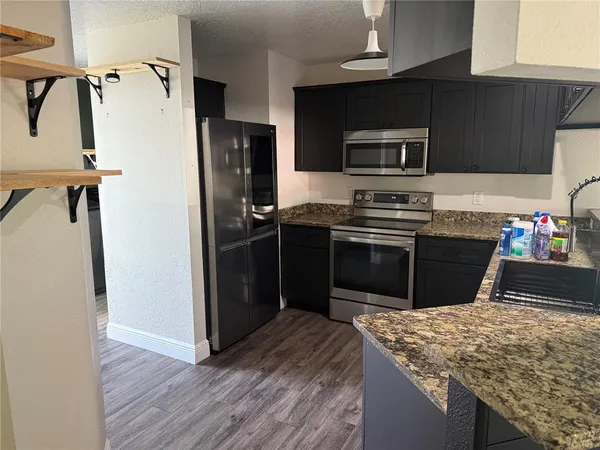 a kitchen with stainless steel appliances granite countertop a refrigerator a stove and a microwave