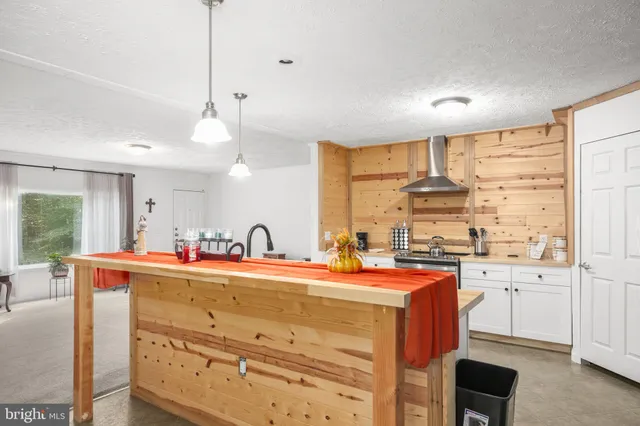 a room with stainless steel appliances kitchen island granite countertop a sink a stove and a cabinets