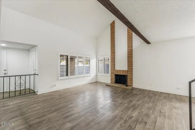 an empty room with wooden floor windows and entryway