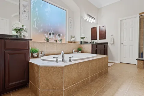 a spacious bathroom with a granite countertop sink a mirror a bathtub and shower
