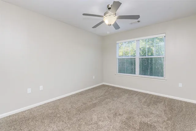 an empty room with a window and a fan