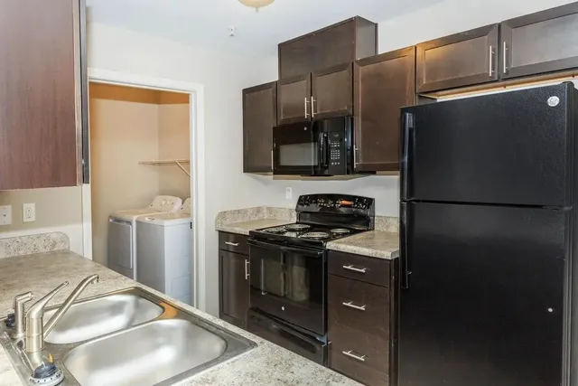 a kitchen with stainless steel appliances granite countertop a refrigerator a stove and a sink with wooden floor