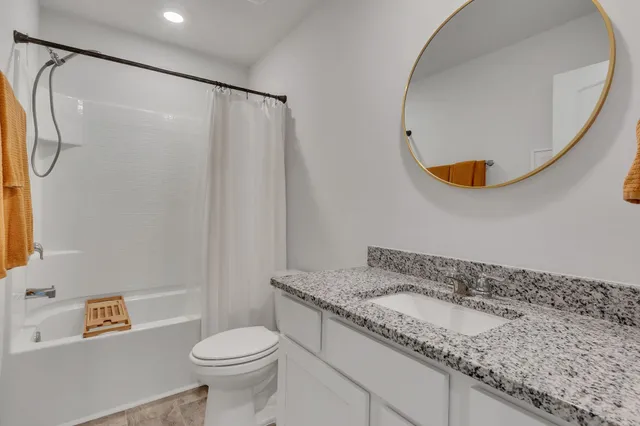 a bathroom with a granite countertop sink toilet and a mirror