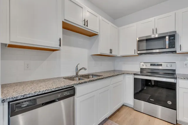 a kitchen with stainless steel appliances granite countertop a sink dishwasher a stove and a microwave oven with cabinets