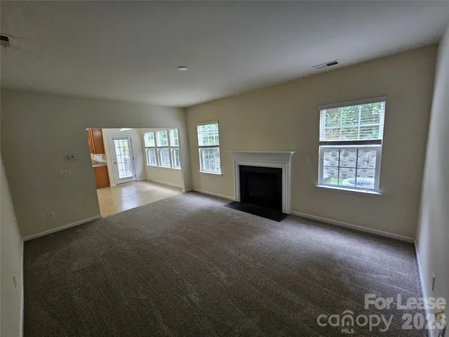 a view of an empty room with a fireplace and a window