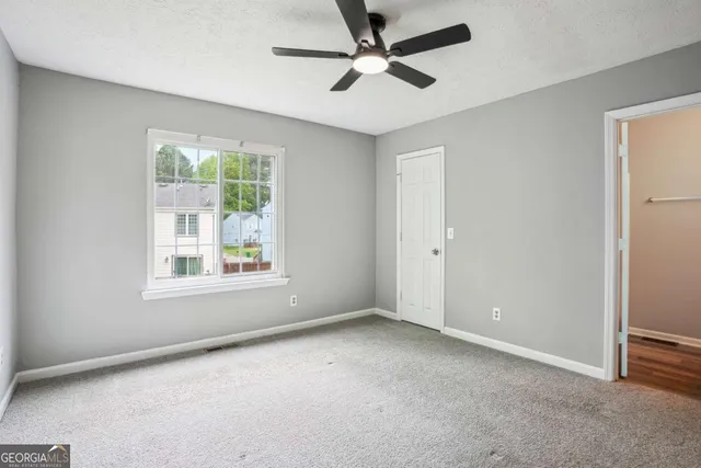 an empty room with a window and a fan
