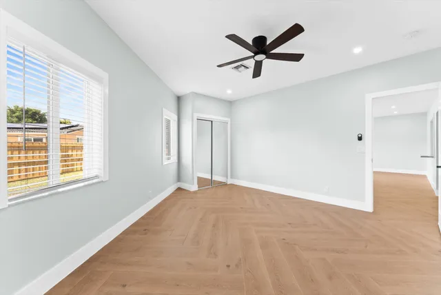 an empty room with a window and a ceiling fan