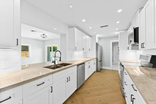 a large kitchen with stainless steel appliances granite countertop a sink and cabinets