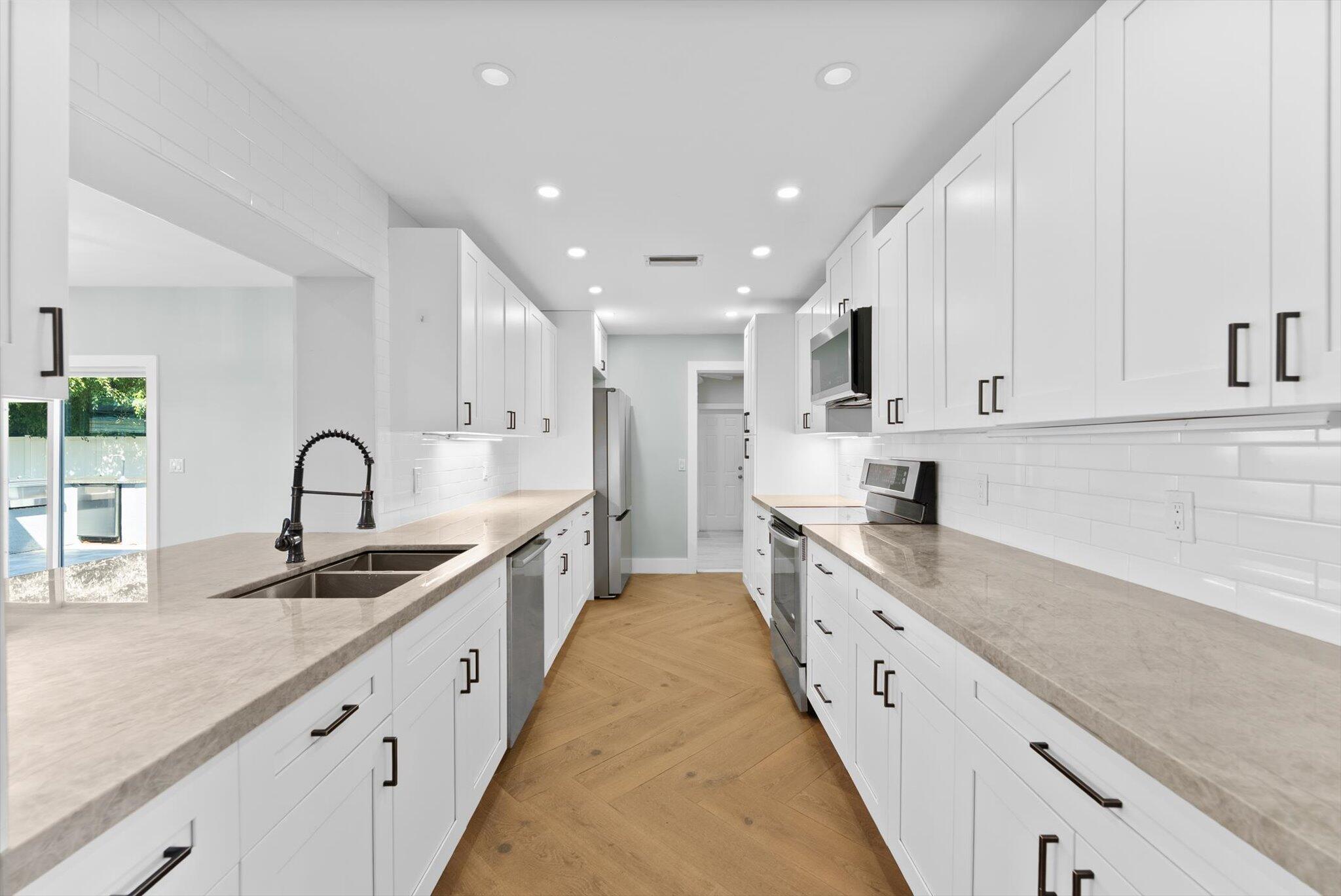 1721 Southwest 10th Street Boca Raton, FL 33486 - Photo 8 of 34 a large kitchen with stainless steel appliances granite countertop a sink and cabinets