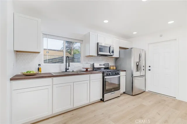 a kitchen with stainless steel appliances granite countertop a sink a stove a refrigerator a microwave a sink and cabinets