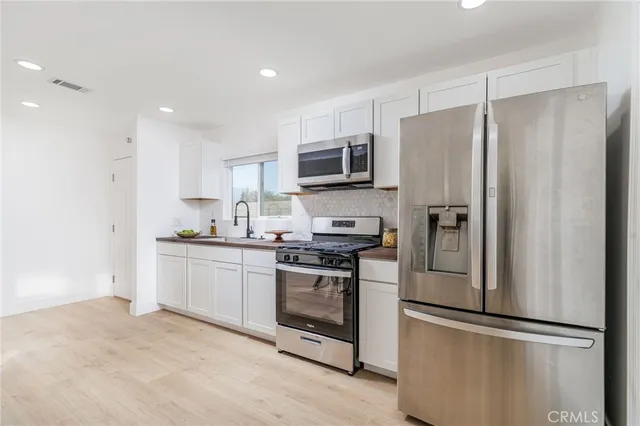 a kitchen with stainless steel appliances granite countertop a refrigerator a stove a sink and a microwave