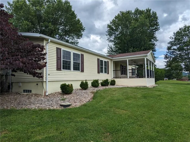 a front view of house with yard and trees in the background