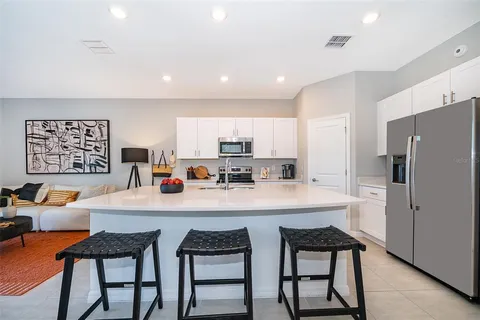a kitchen that has a lot of white cabinets and stainless steel appliances