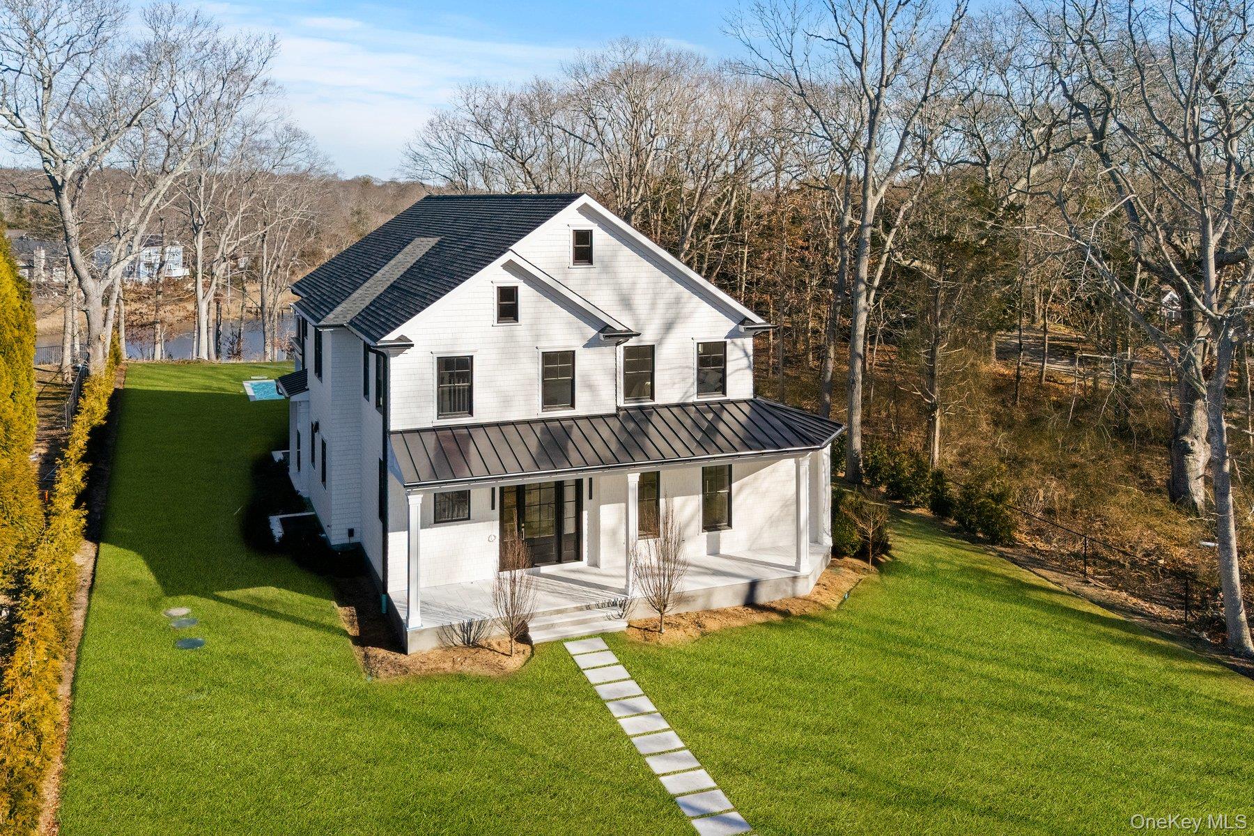 2590 Cox Neck Road Mattituck, NY 11952 - Photo 45 of 50 View of front of home with a porch, a standing seam roof, a front lawn, a metal roof, and a shingled roof