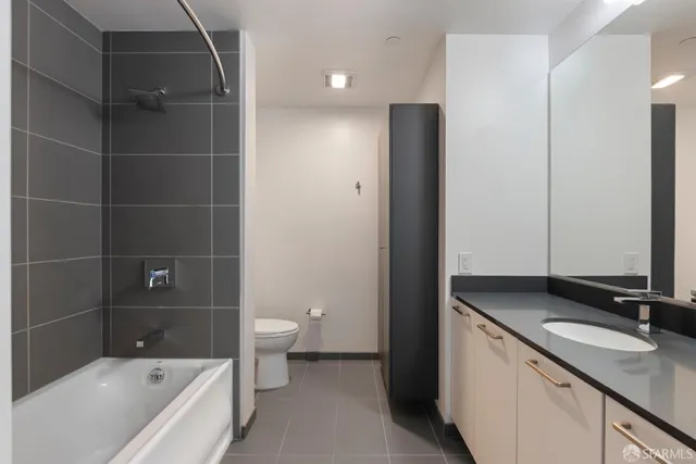 a bathroom with a granite countertop sink a toilet and shower
